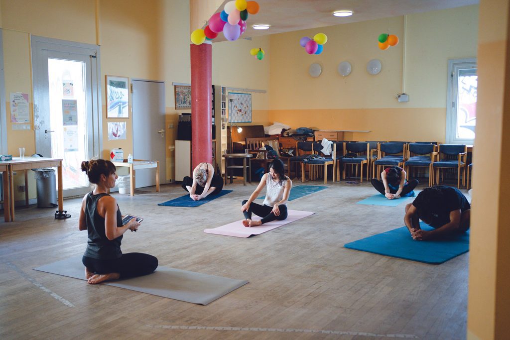 A group seated on mats in a circle during a movement session