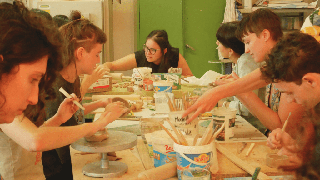 Many people working with clay at a pottery workshop table
