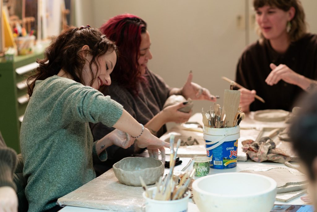 A group working with clay together at a pottery workshop table