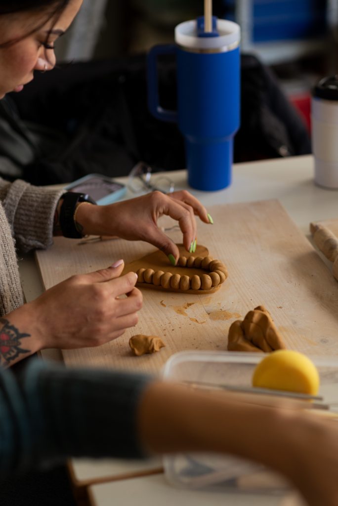 A person decorating a clay piece at a pottery workshop