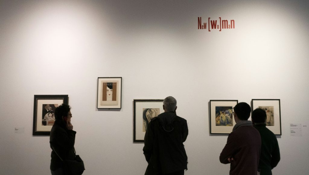 People viewing framed artworks on a gallery wall