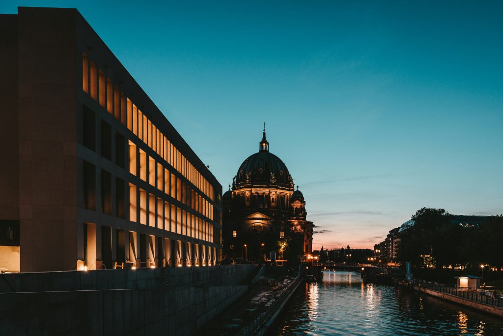 The Berlin Cathedral and a riverside building at dusk