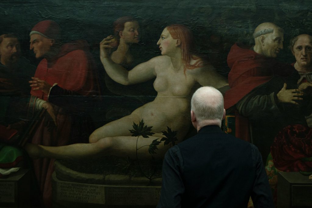 A person viewing a classical painting in an art gallery