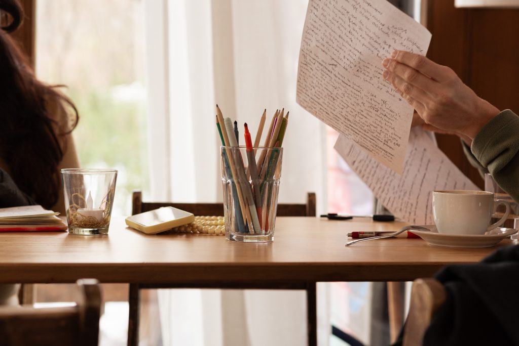 A person reading a handwritten letter at a table during a creative writing session
